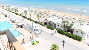 Un hotel frente a la playa con varias piscinas, un espacio al aire libre techado y vistas a la playa y al océano.
