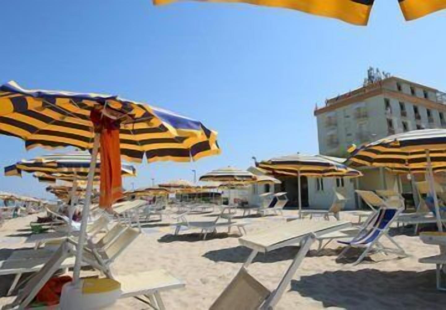 A beach with multiple sun umbrellas and lounge chairs.