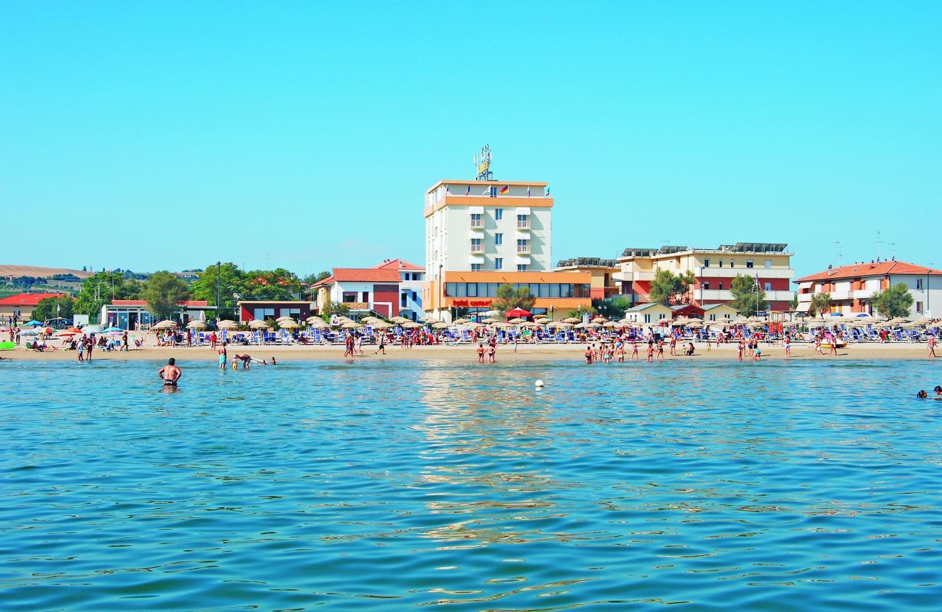 A coastal area with a beach, buildings, and a clear sky.
