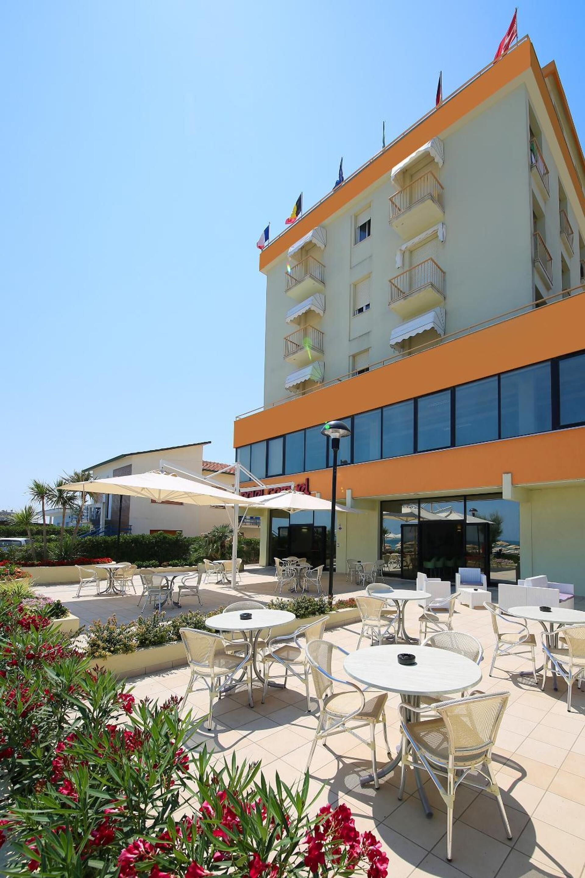 Un hotel con terraza, piscina y un edificio con balcones.