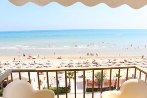 A beach view from a balcony with sun loungers and umbrellas. - Hotel Caravel (Fano)