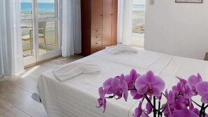 Un dormitorio con cama, un armario de madera y vista a la playa.