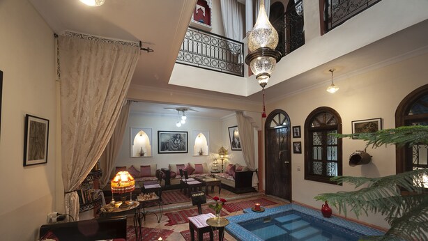 Amplia sala de estar con piscina, asientos cómodos y un balcón con barandilla decorativa.