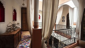 Un interior tradicional con un aparador de madera, un tapete estampado y un balcón con barandilla de hierro forjado.