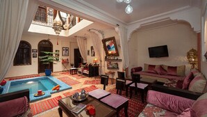 Amplia sala de estar con piscina, asientos cómodos y televisor.