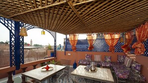 Un espacio al aire libre con mesas y sillas, un muro con diseño y vistas a la ciudad.