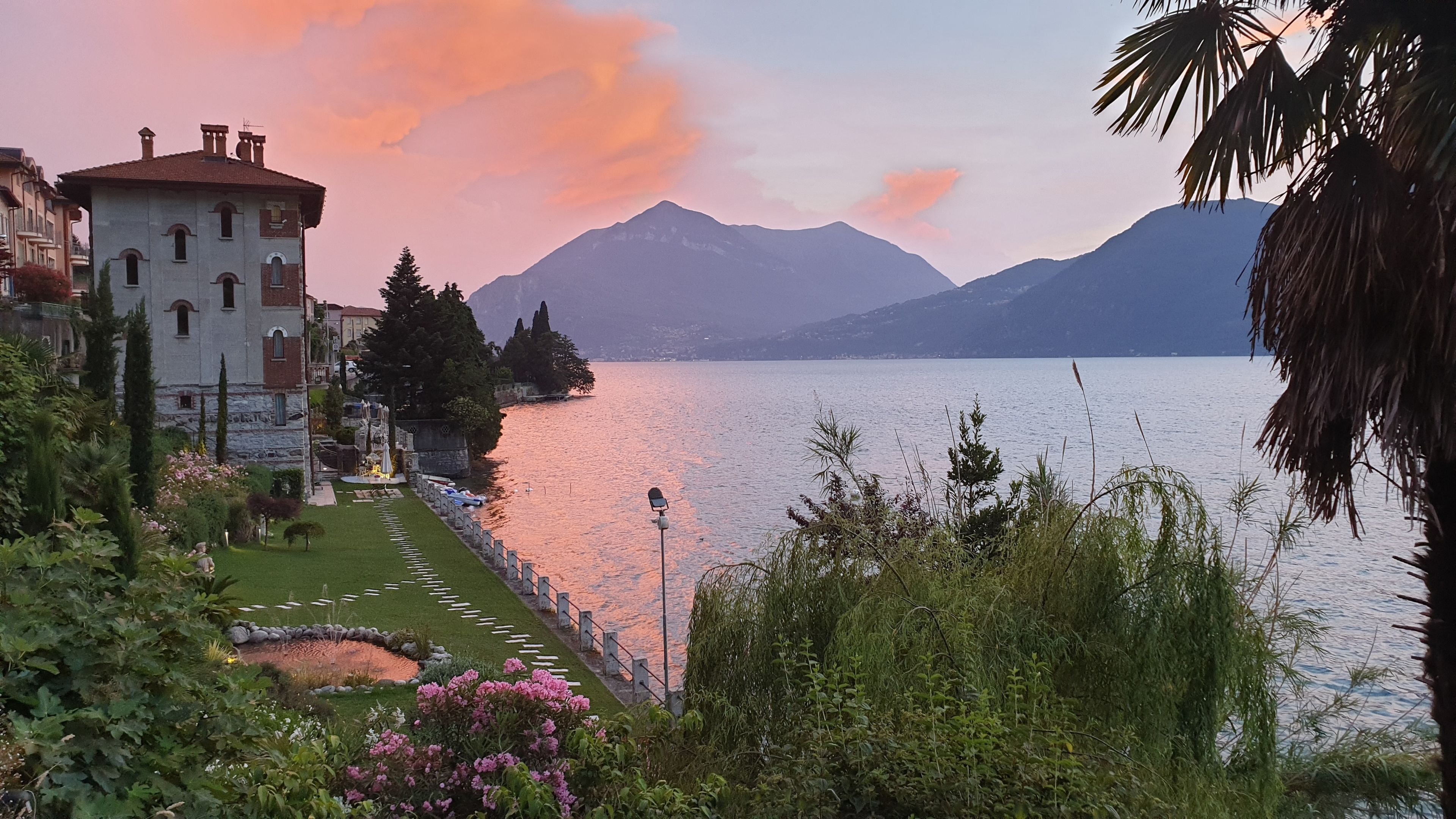 A lakeside view with a building featuring a garden and a statue.
