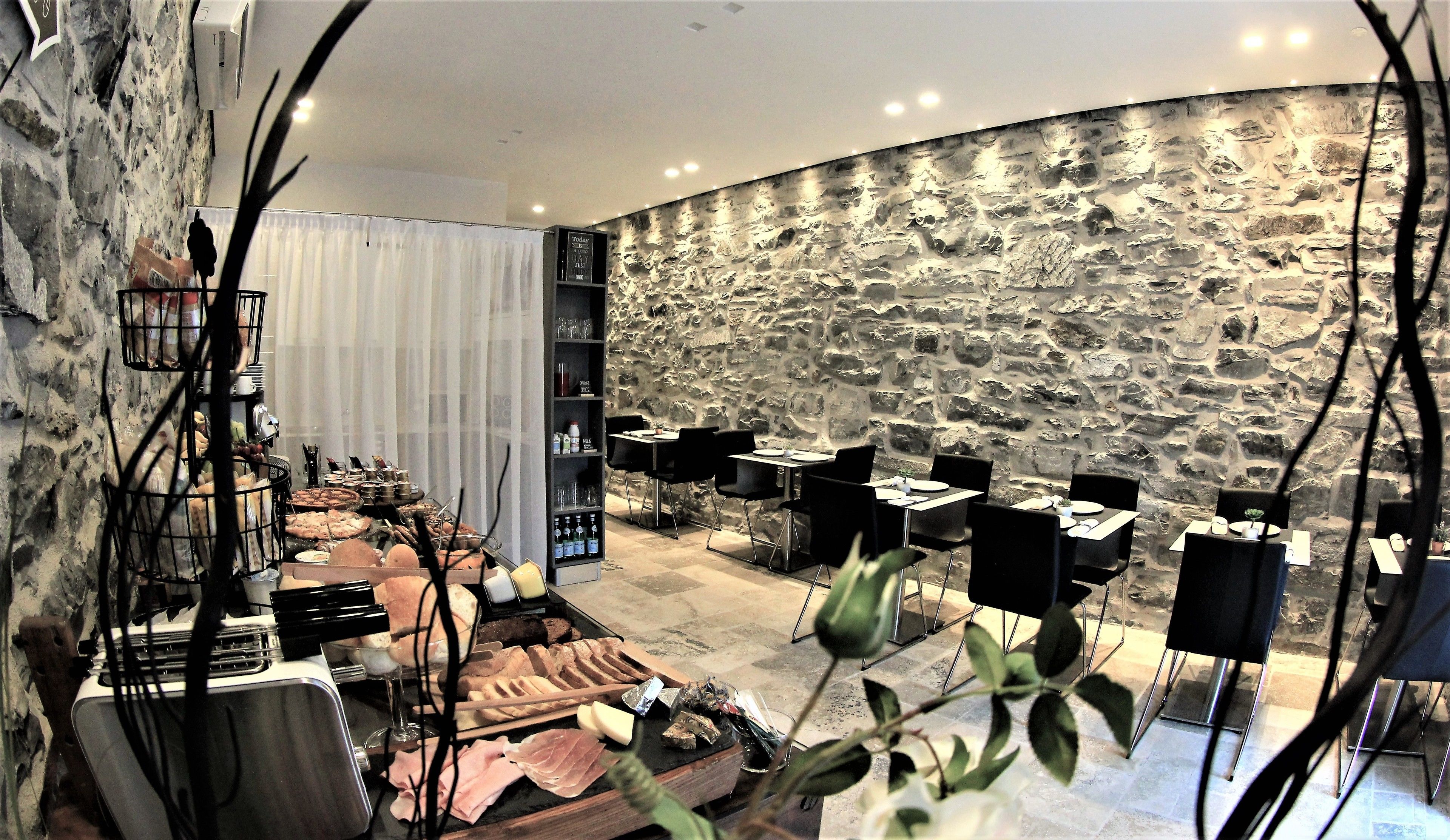 Ein Restaurant mit Steinsandsteinwänden, mehreren Tischen und Stühlen.