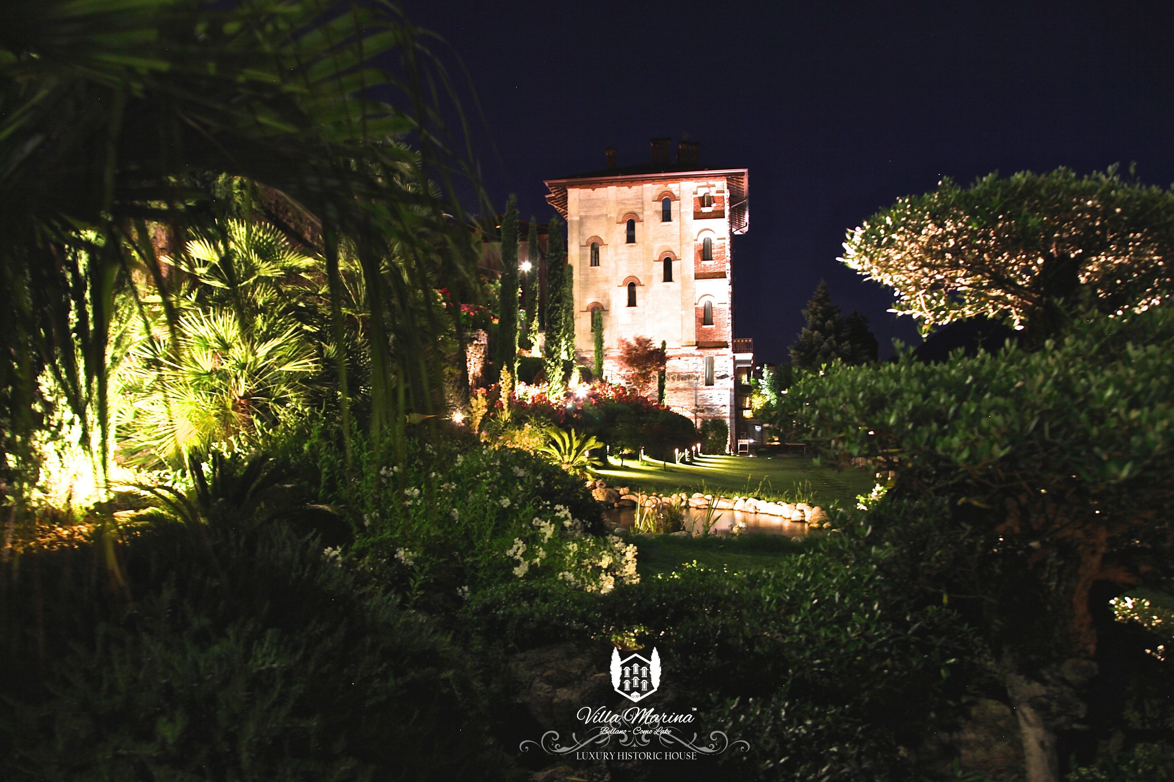A historic house with a well-lit garden at night.