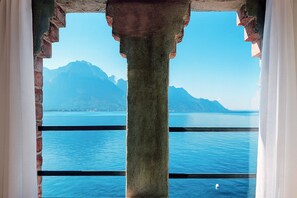 A view through a window with a stone column, a clear blue sky, and a mountain in the distance. - Villa Marina - Como Lake (Bellano)