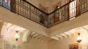 Interior de varios niveles con un patio central, que incluye un conjunto de sofás, plantas en macetas y faroles decorativos.
