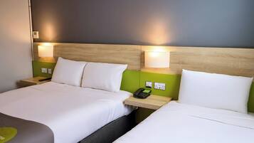 A hotel room with two beds, a bedside telephone, and a green wall.