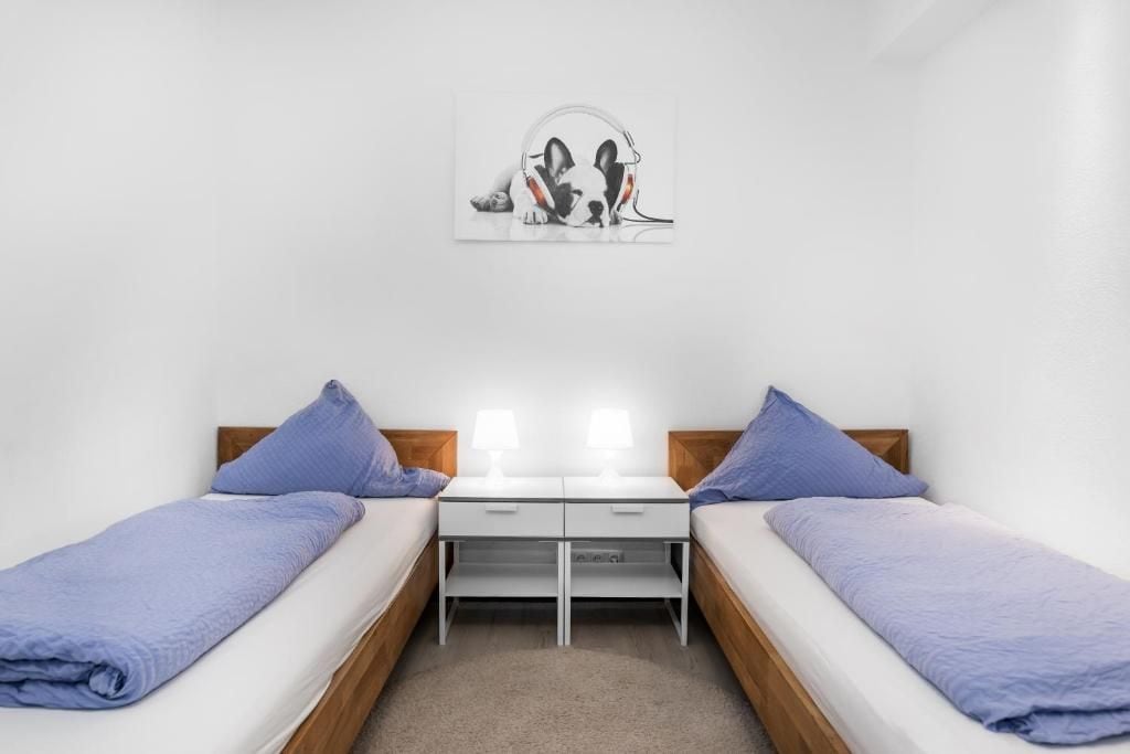 A twin room with two beds, a small table, and a wall-mounted artwork.