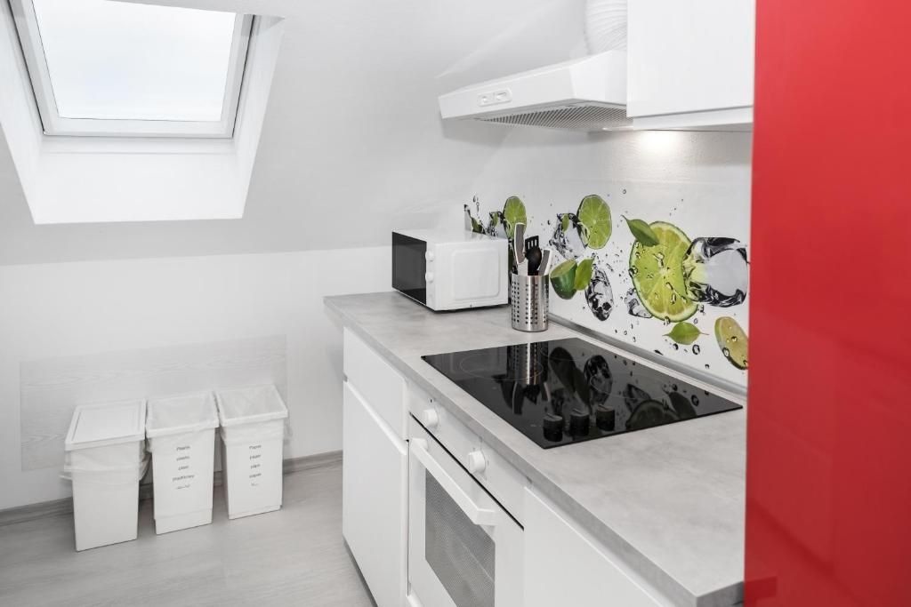 A modern kitchen with a skylight, white cabinets, a microwave, and a backsplash with lime illustrations.