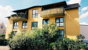 A multi-story building with balconies and windows, surrounded by dense greenery. - Pension Genat (Wedemark)