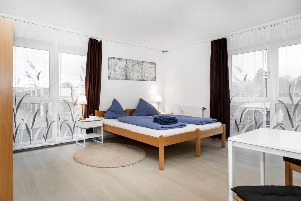 A modern bedroom with a wooden bed, a bedside table, a chair, and a view through large windows.
