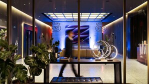 Un hall d’hôtel moderne doté d’un espace salon central, d’un comptoir d’accueil et d’une cloison en verre.