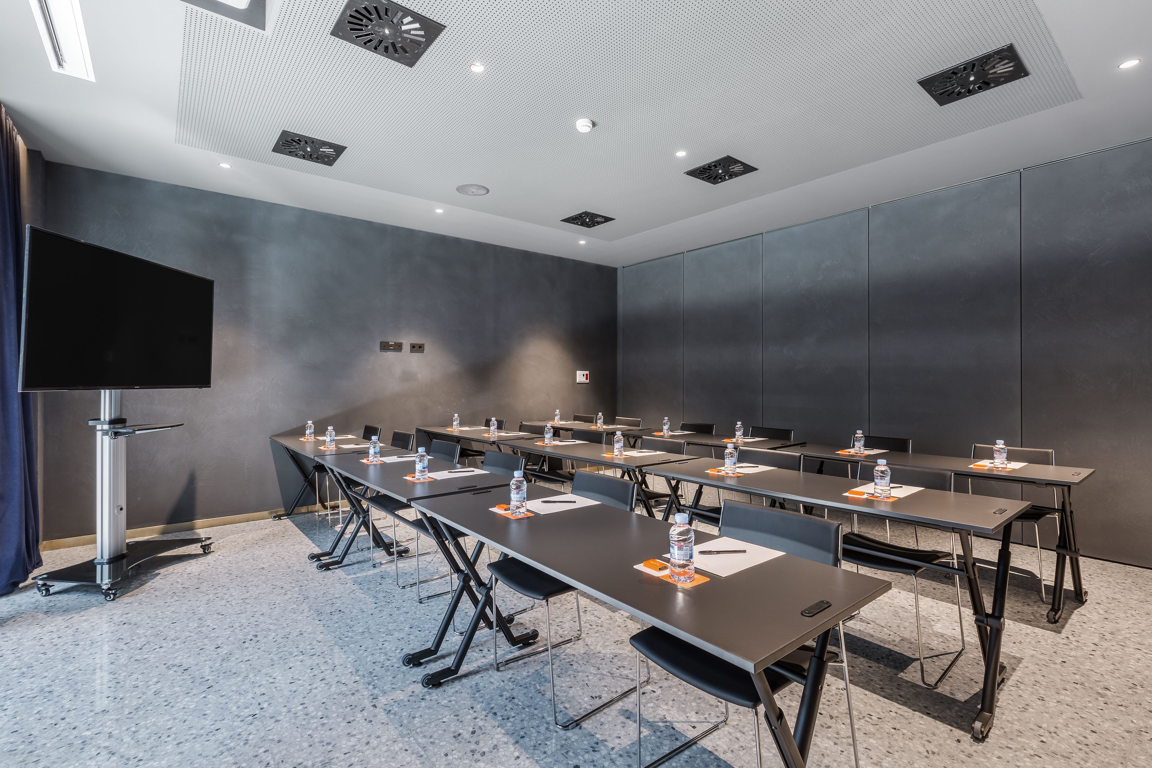 Une salle de conférence équipée de plusieurs tables, de chaises et d’un grand écran.