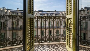 Une vue à travers des barreaux en métal ouvragés, donnant sur un immeuble doté de nombreux balcons et fenêtres.