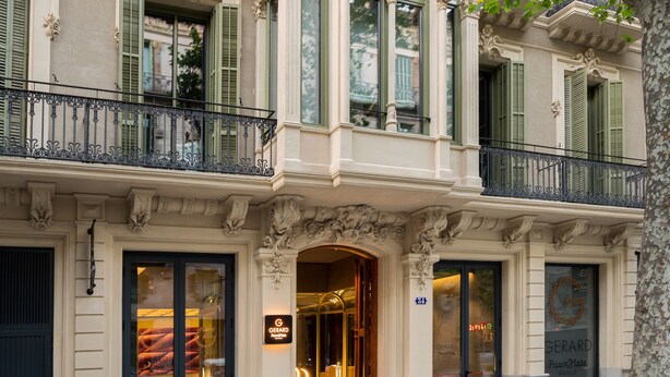 La façade d’un hôtel, ornée de détails architecturaux raffinés, dotée de grandes fenêtres en verre et d’une entrée imposante.