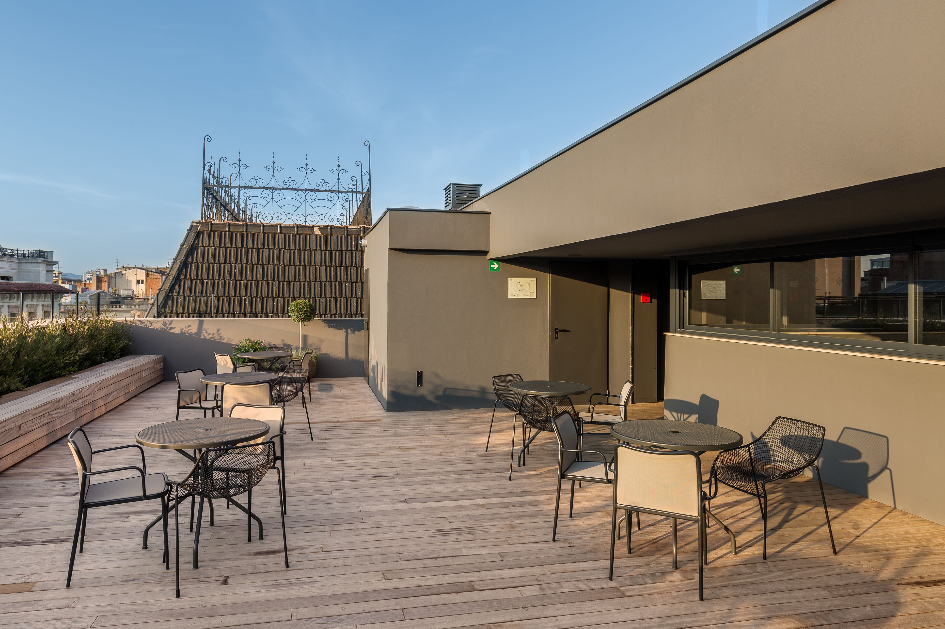 Eine Dachterrasse mit Sitzgelegenheiten im Freien und Blick auf die Stadt.