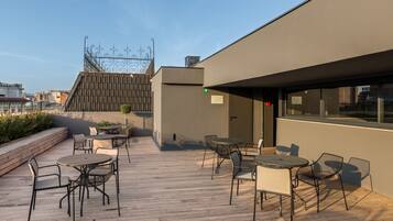 Eine Dachterrasse mit Sitzgelegenheiten im Freien und Blick auf die Stadt.