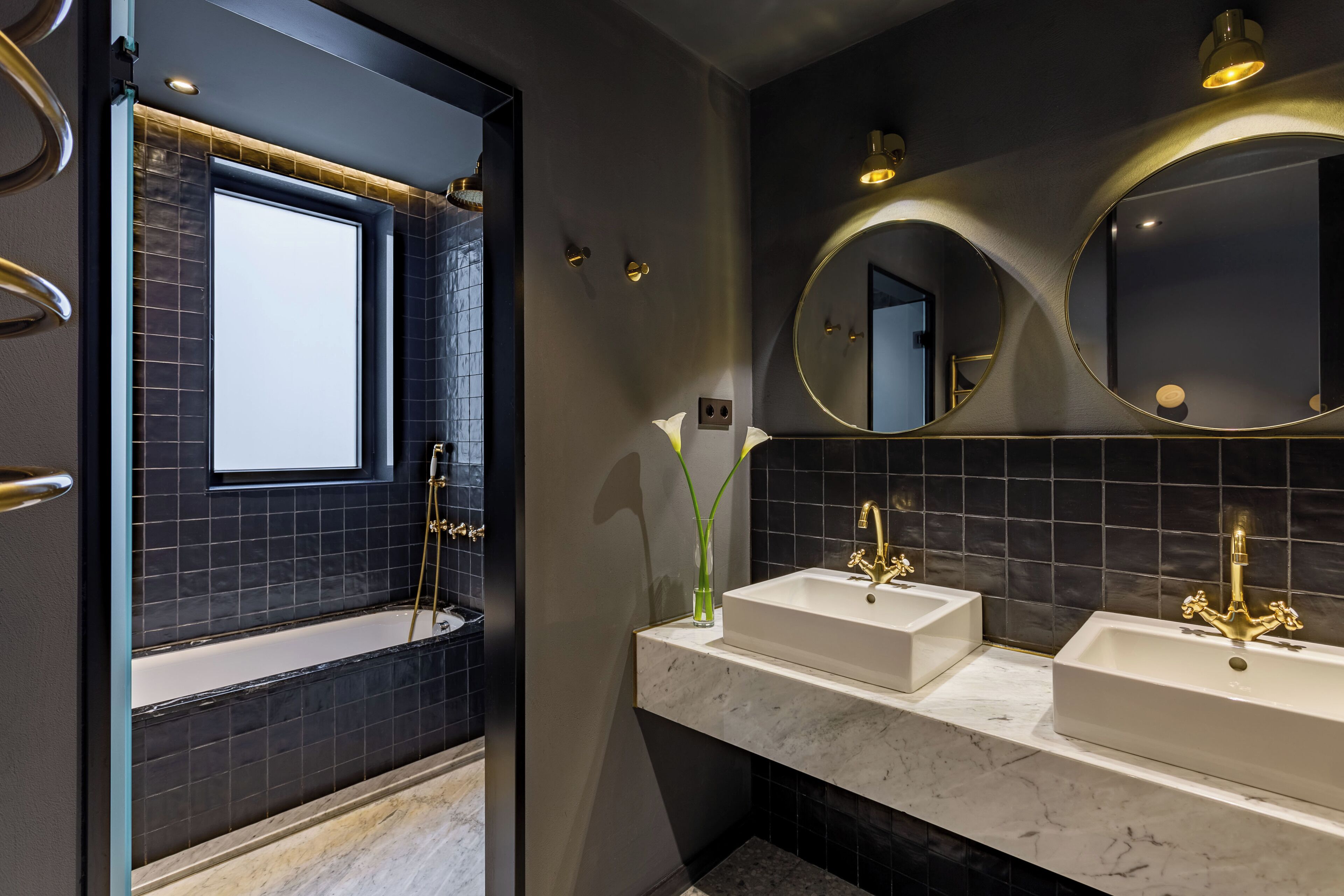 A modern bathroom with a bathtub, two sinks, and a large mirror.