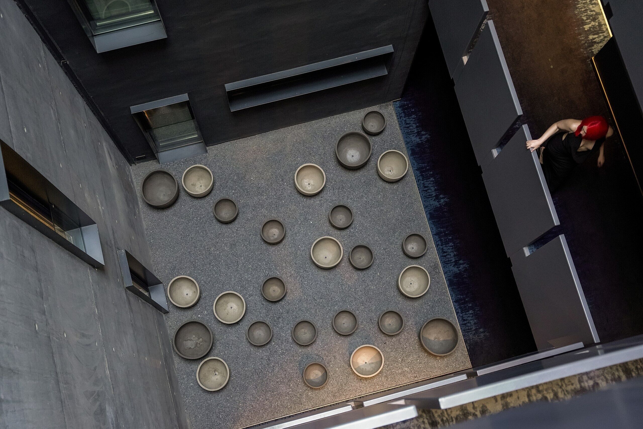 Eine Dachterrasse mit mehreren runden Sitzbereichen, modernem architektonischen Design und einer Person in roter Kleidung.