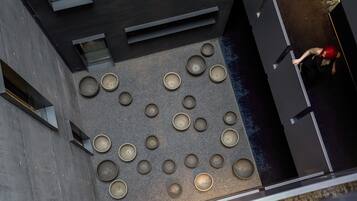 Eine Dachterrasse mit mehreren runden Sitzbereichen, modernem architektonischen Design und einer Person in roter Kleidung.