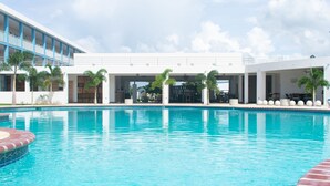 A swimming pool with a clear blue water, surrounded by a modern building with balconies and palm trees. - Punta Borinquen Resort (Aguadilla)