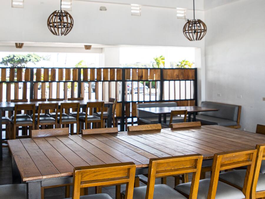 A restaurant with wooden tables and chairs, a blue ceiling, and hanging light fixtures.
