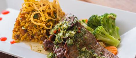 A plate of food with a piece of meat, rice, and vegetables.