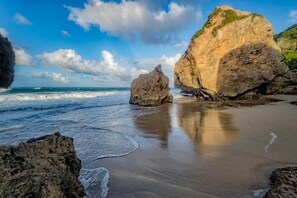 Una playa con grandes rocas y olas.