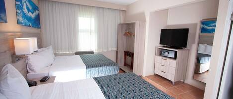 A hotel room with two beds, a TV, a wardrobe, and a bathroom visible through an open door.