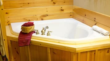 Une salle de bain de style rustique, avec des murs en bois, une baignoire, deux robinets et des serviettes.