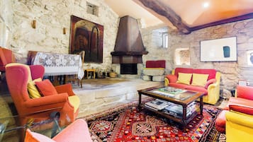 Un salón acogedor con paredes de piedra, chimenea y asientos coloridos.