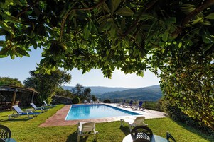 Una piscina con sillones de descanso y vistas a las colinas.