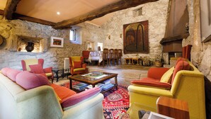 A rustic interior with stone walls, wooden beams, and colorful furniture. - Rectoral de Fofe (Covelo)