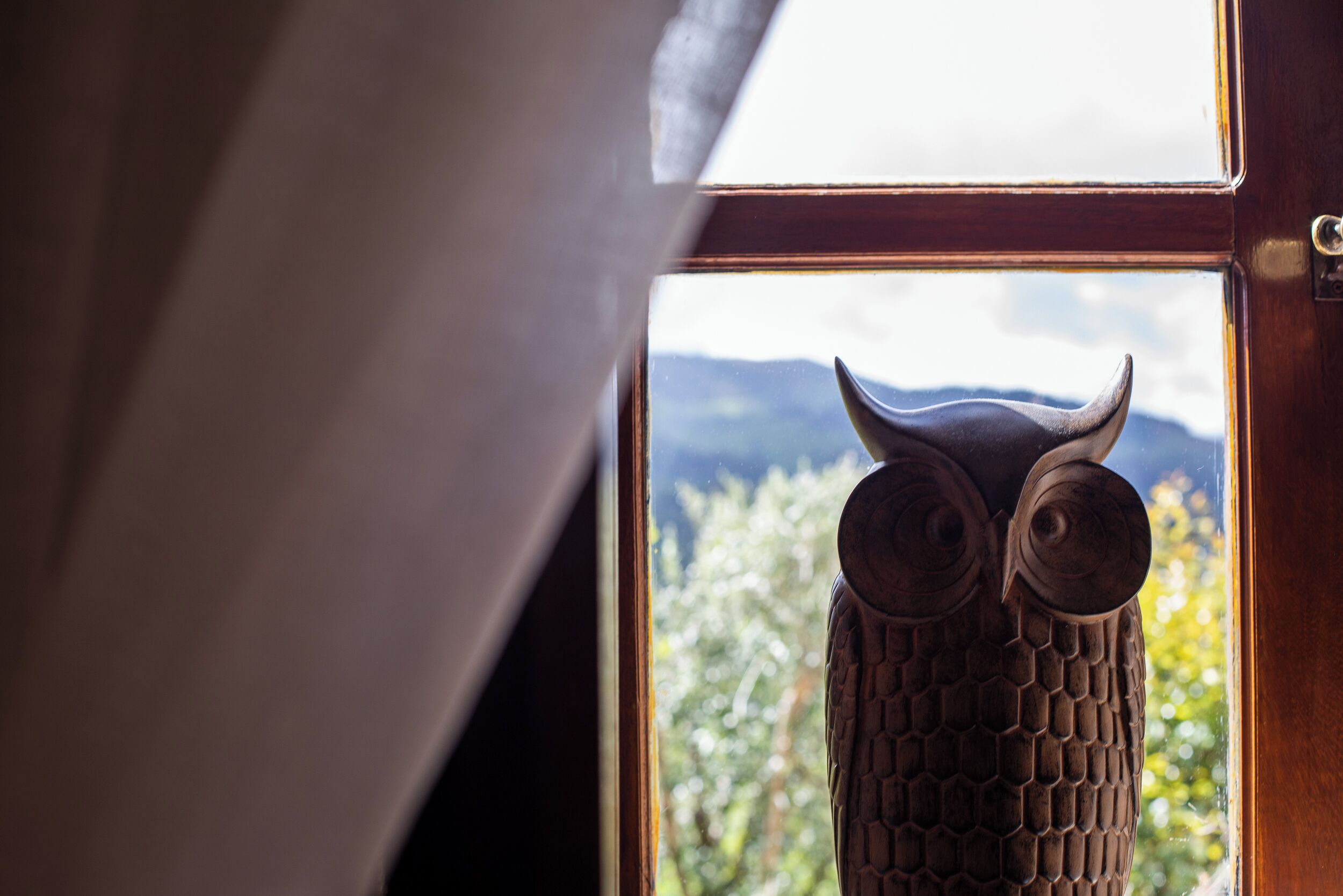A wooden owl sculpture in a window.
