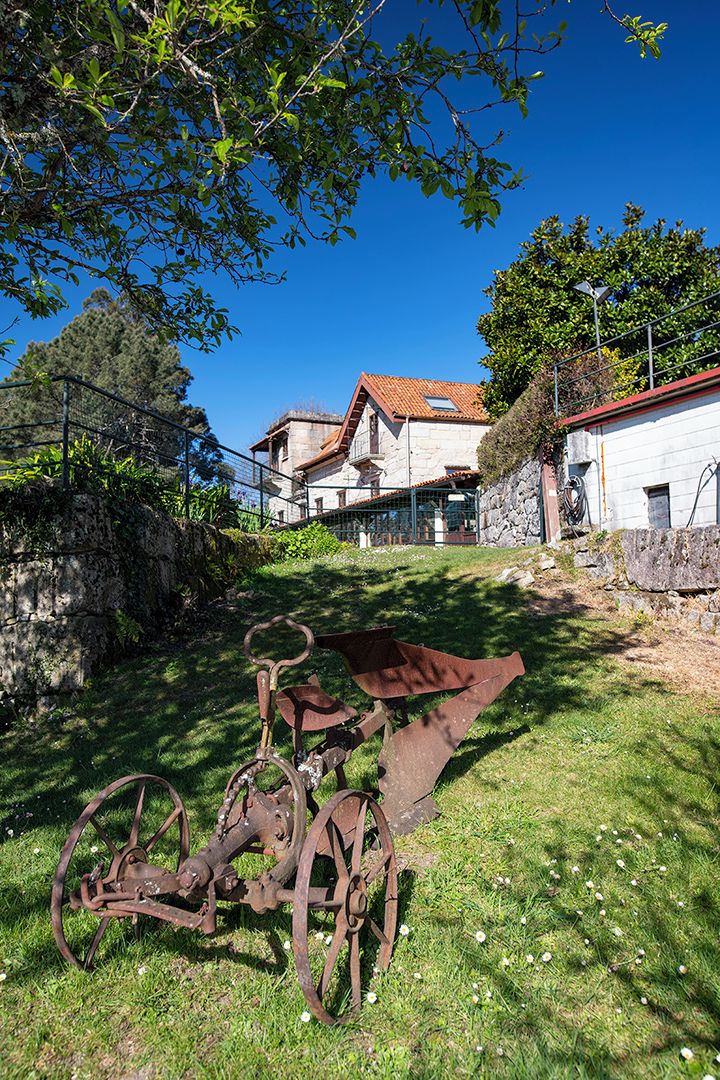 A rustic outdoor area with a metal structure, a stone wall, and a building with a tiled roof.