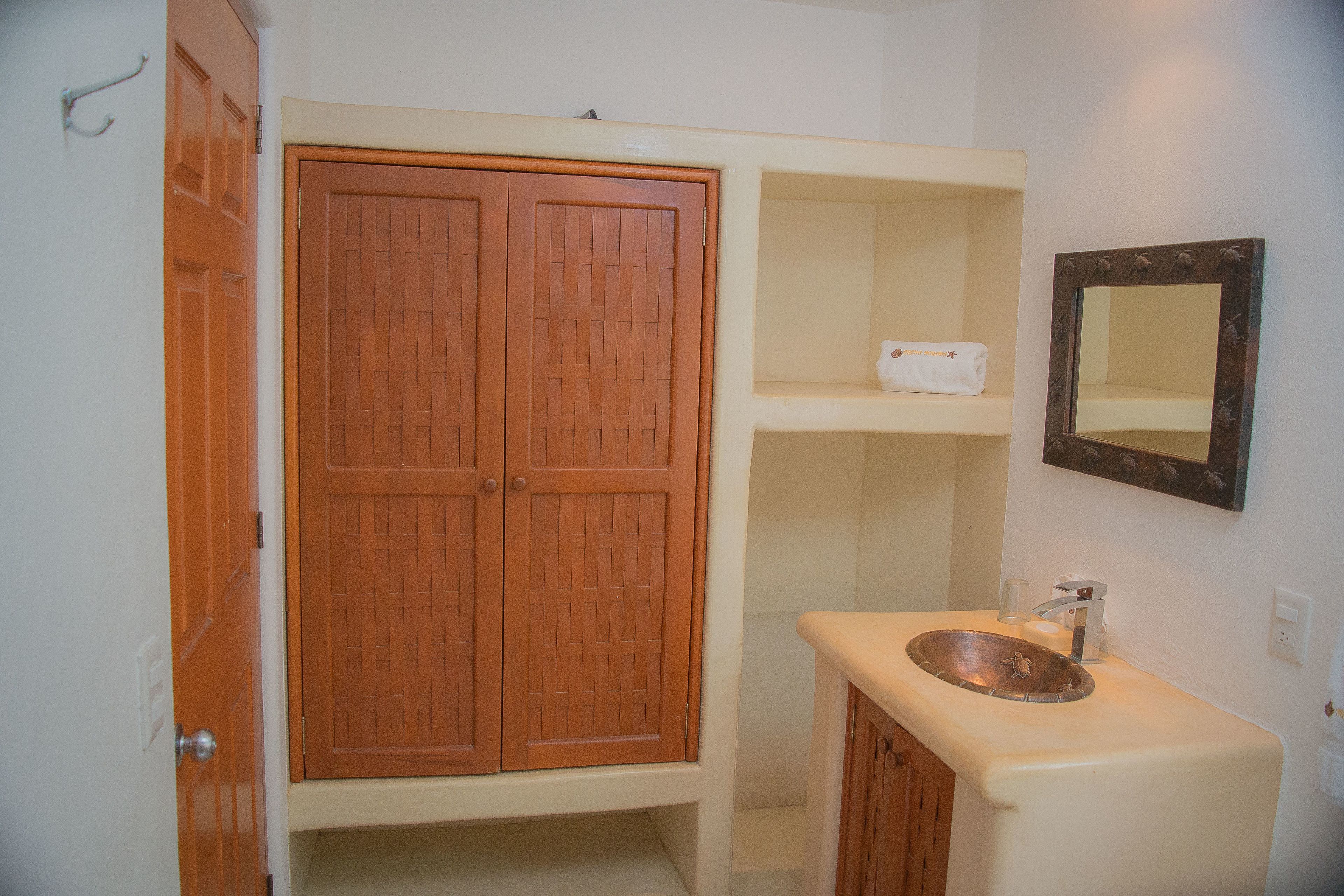 Un baño con un armario de madera, un lavabo con espejo y una toalla en la repisa.