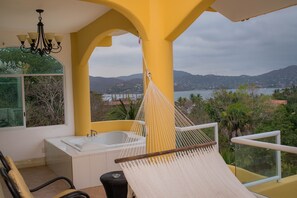 A balcony with a hammock, a bathtub, and a view of a lake and mountains. - Hotel Bungalows Arena Dorada - Adults Only (Zihuatanejo)