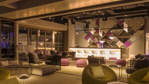 Et moderne loungeområde med siddepladser, bar og udsigt over bybilledet.