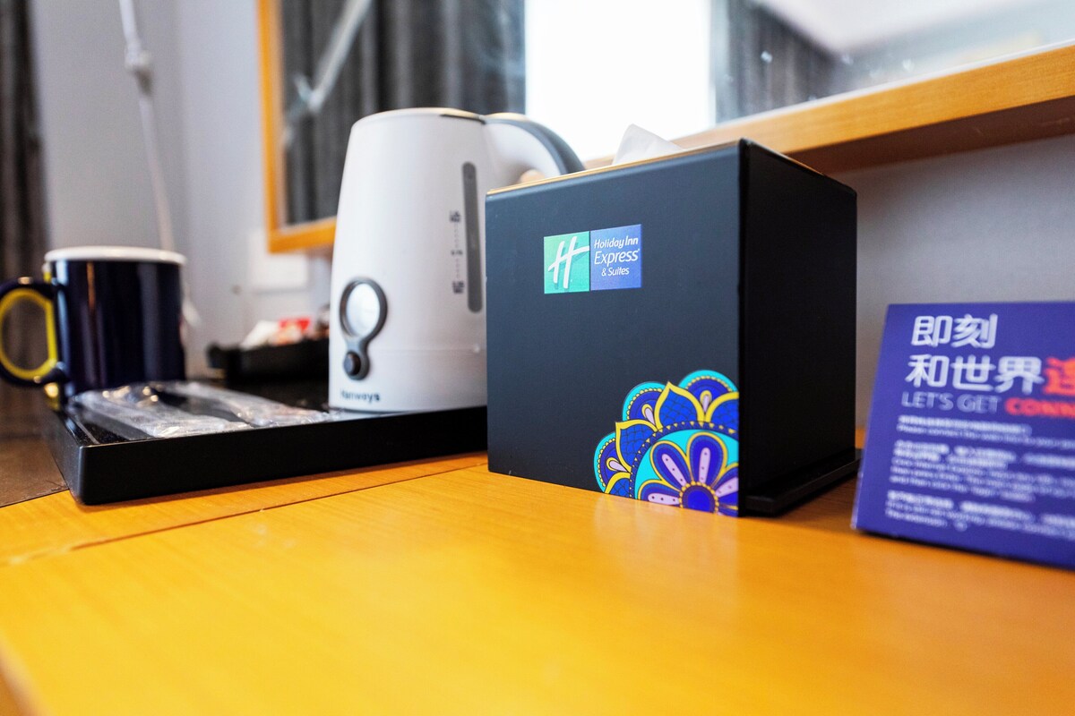 A coffee maker, a box with a logo, and a sign on a wooden surface.