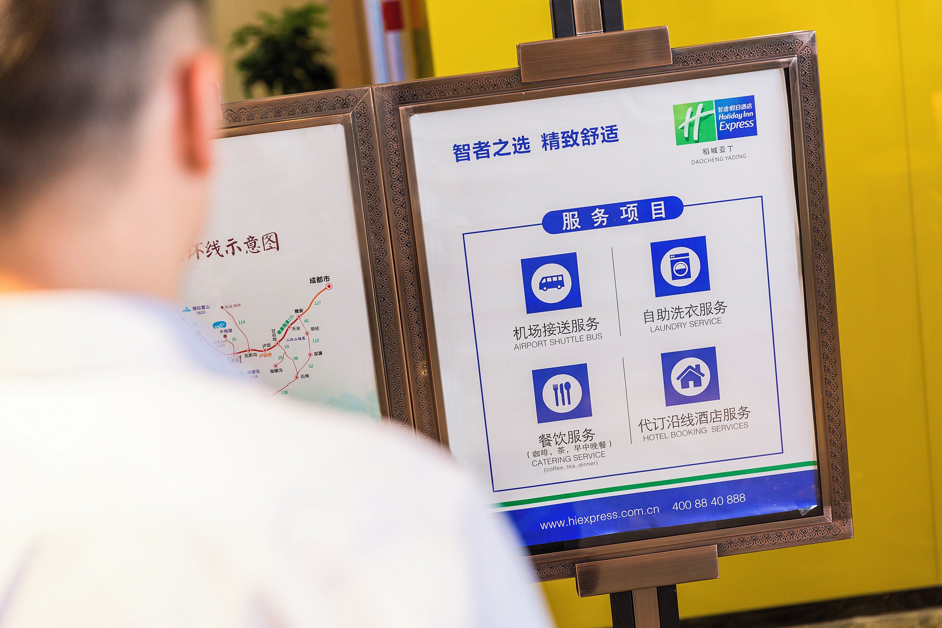 A hotel information board with amenities listed, including shuttle bus service, laundry service, catering service, and hotel booking services.