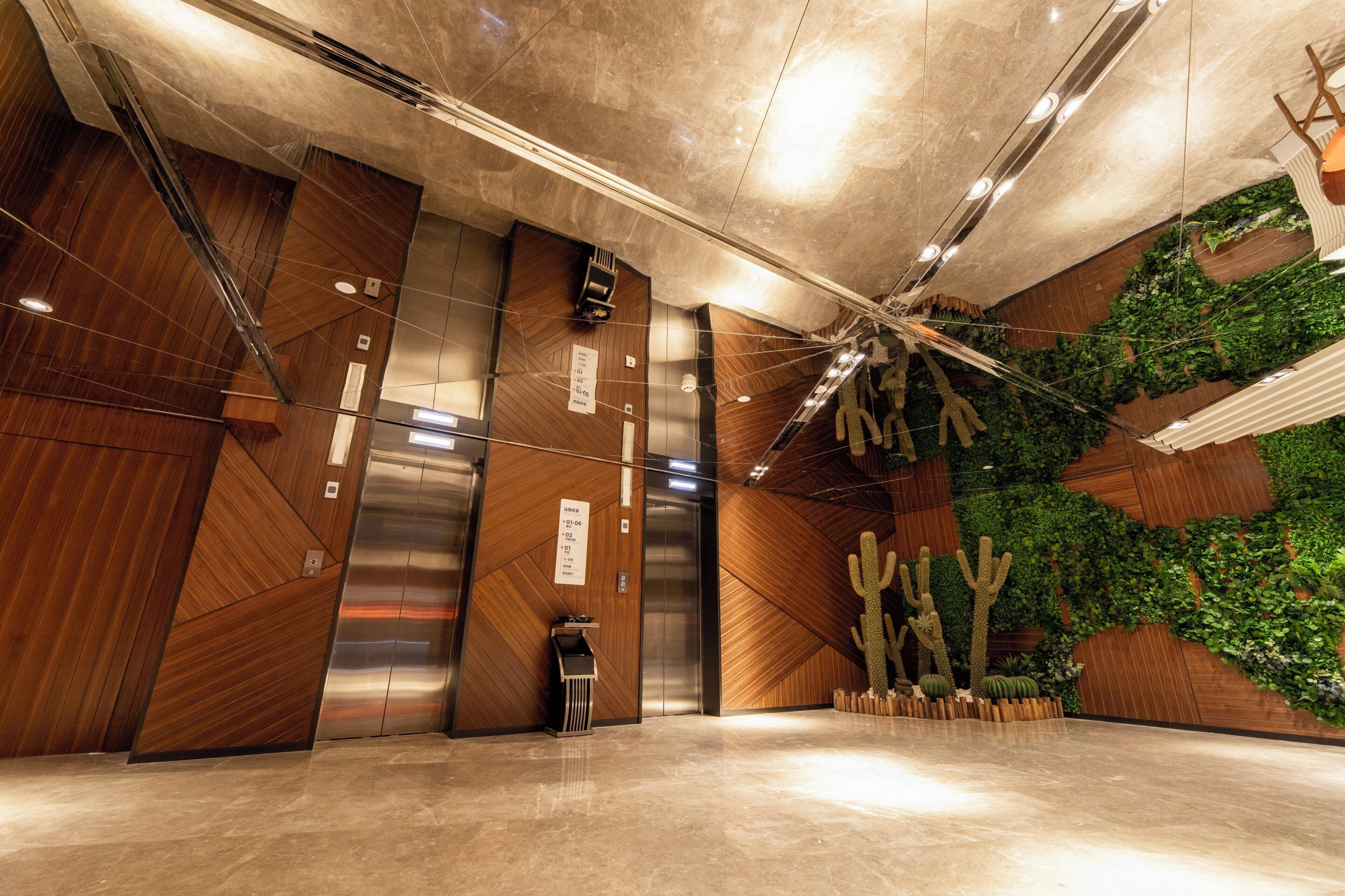A modern elevator with a digital display, a wooden wall with a geometric pattern, and a green wall with plants.
