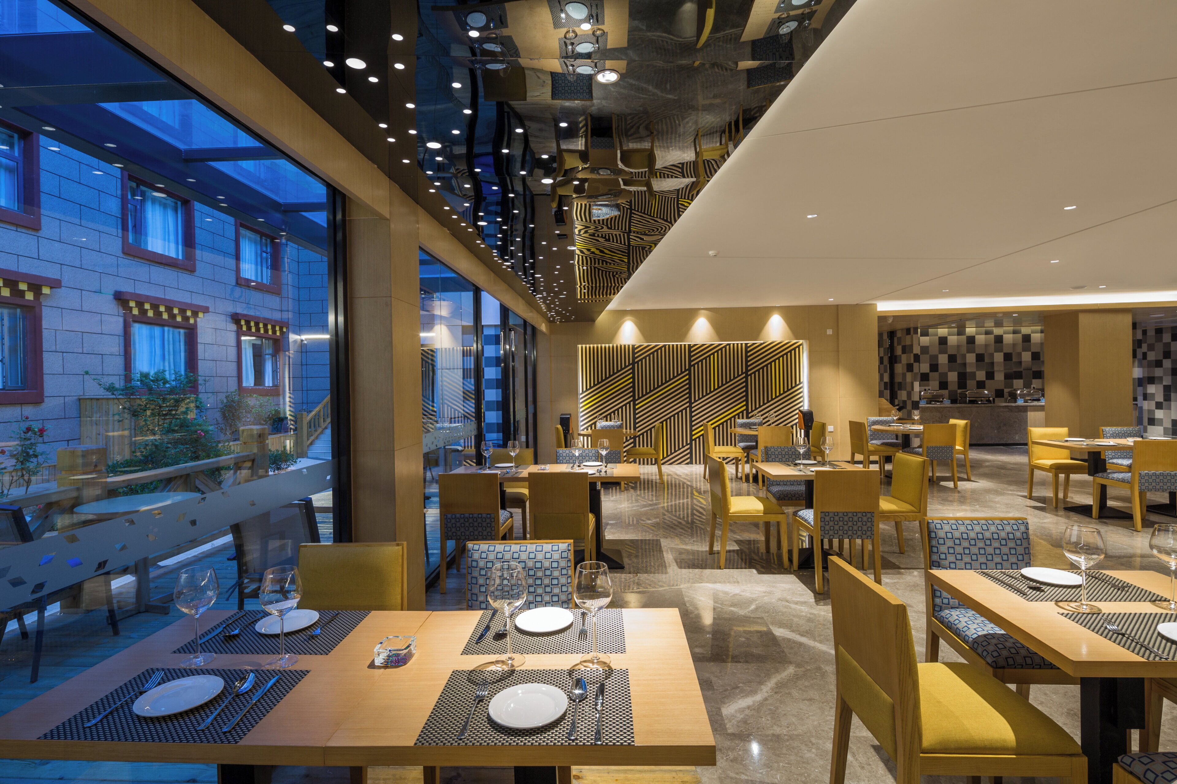 Un restaurant moderne doté de plusieurs tables, de chaises et d’un mur décoré d’un motif particulier en arrière-plan.
