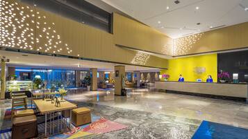 A spacious lobby with a reception desk, seating area, and a glass wall offering a view of the outside.