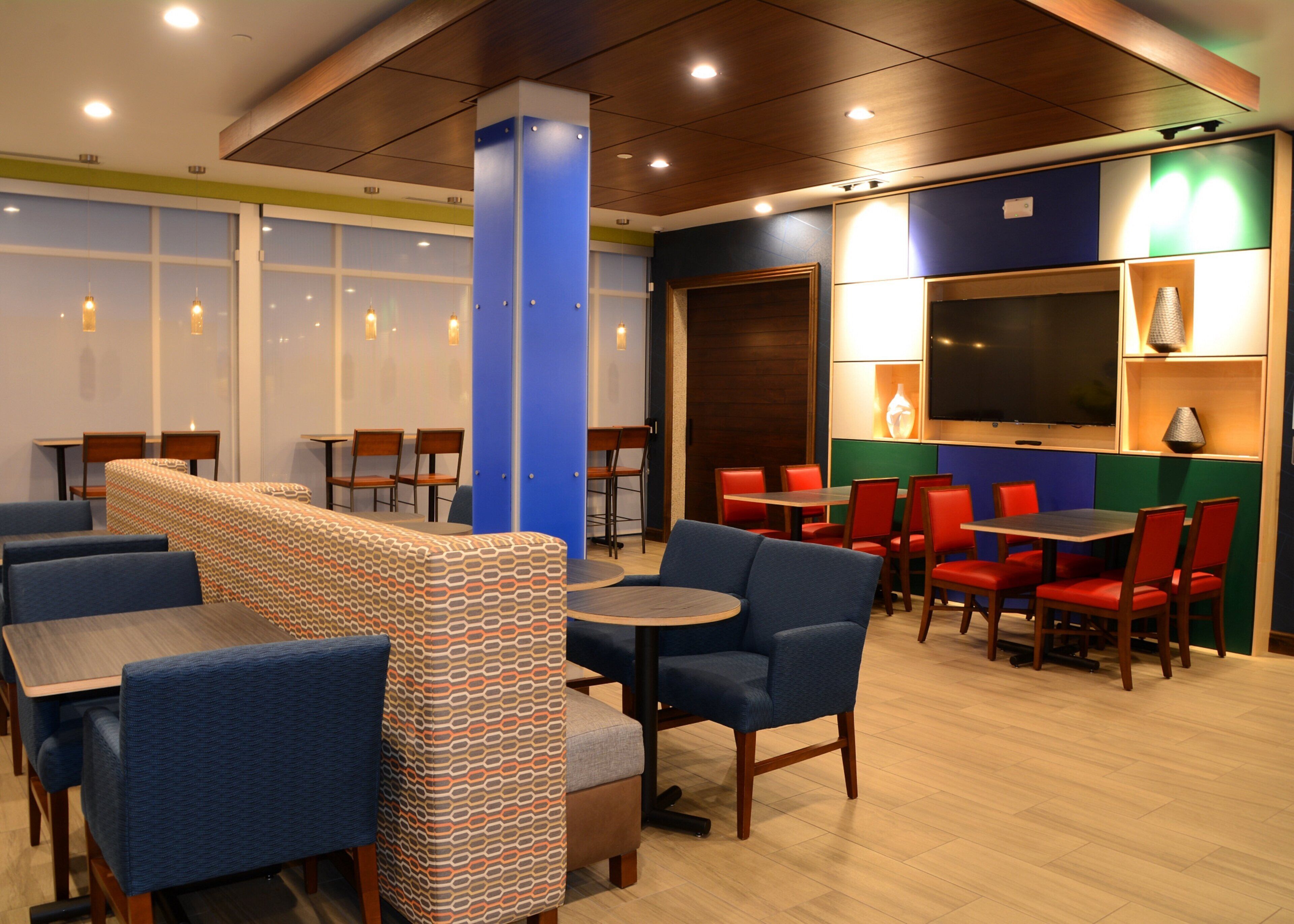 A restaurant with booths, tables, and chairs. There are windows and a television.