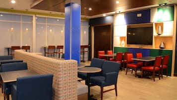 A restaurant with booths, tables, and chairs. There are windows and a television.